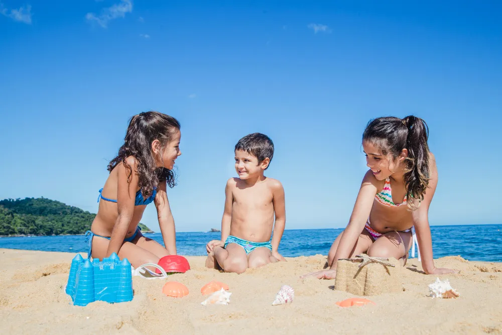 children playing with toys and building sand castles on a beach vacation