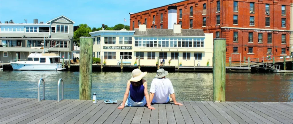 A Couple Enjoying the Mystic Connecticut Attractions Sitting on Water Bay